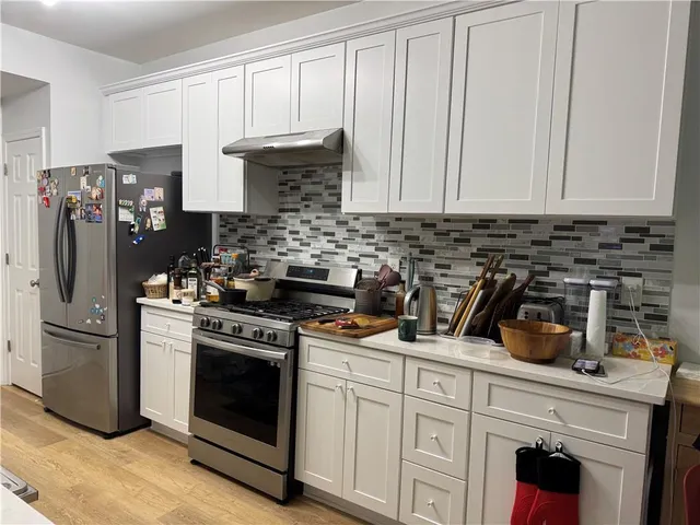 a kitchen with stainless steel appliances granite countertop a stove a refrigerator and a white cabinets