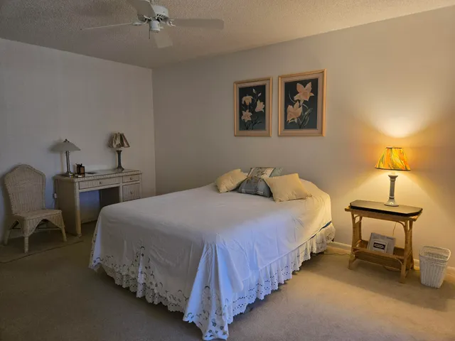 a bedroom with a bed painting on wall and a large window