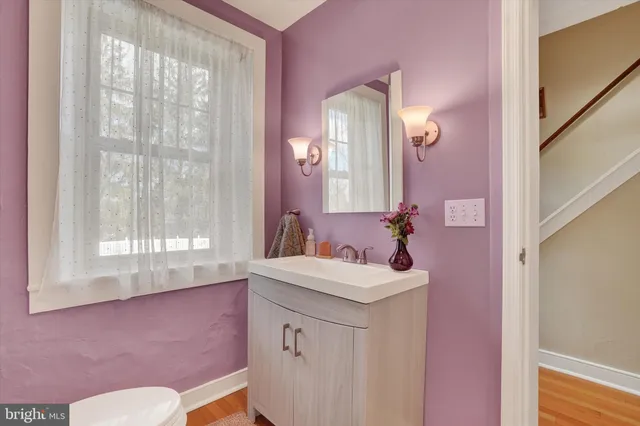 a bathroom with a sink a toilet a mirror and a window