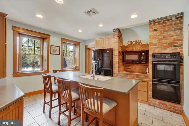 a kitchen with stainless steel appliances granite countertop a refrigerator a stove and a sink with wooden floor