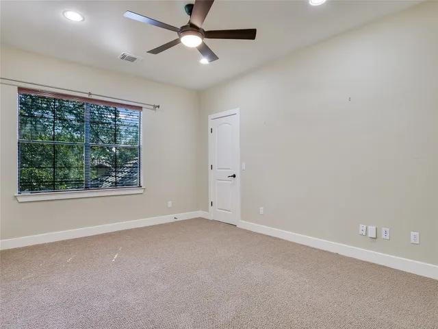 an empty room with a window and a ceiling fan