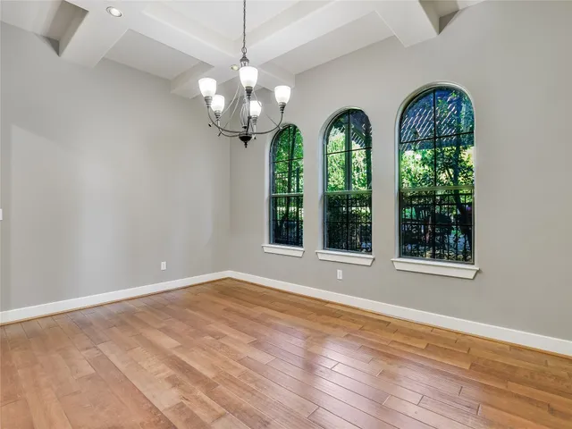 a view of a room with wooden floors a chandelier and a window