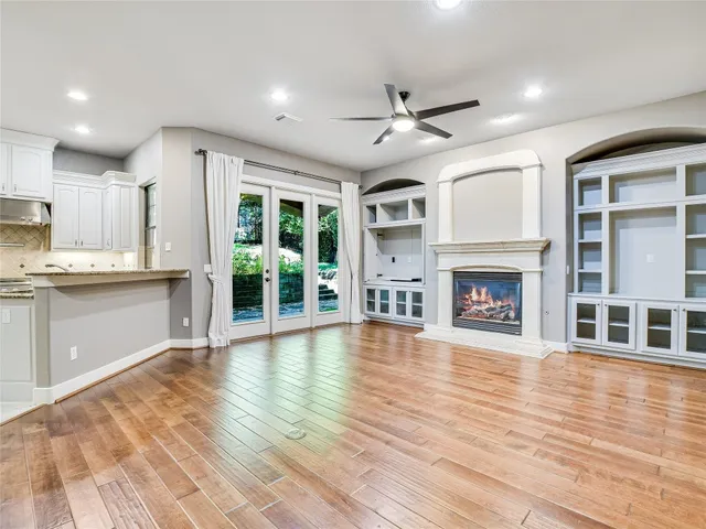 a view of an empty room with wooden floor and a kitchen