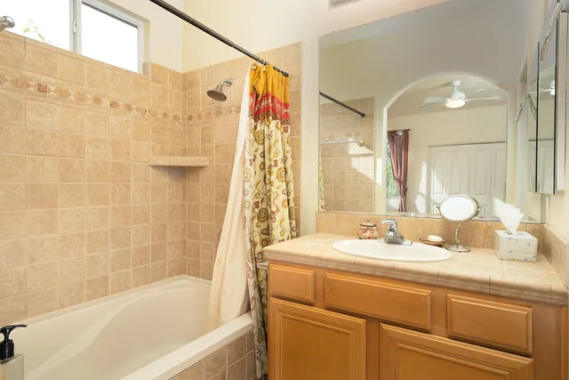 a bathroom with a granite countertop sink mirror and a bathtub