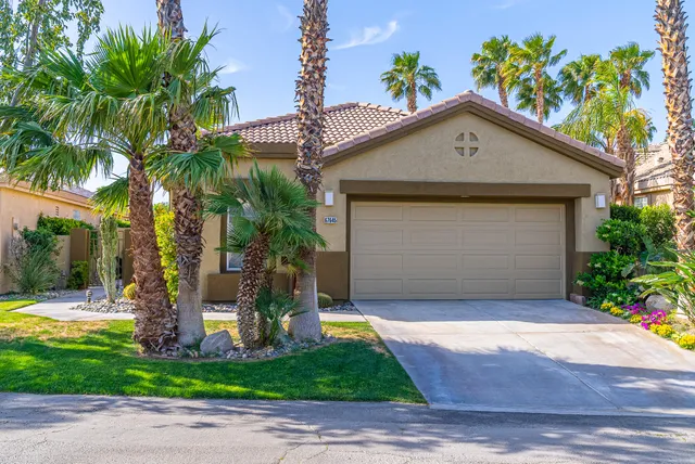 a view of a house with small yard plants and palm trees
