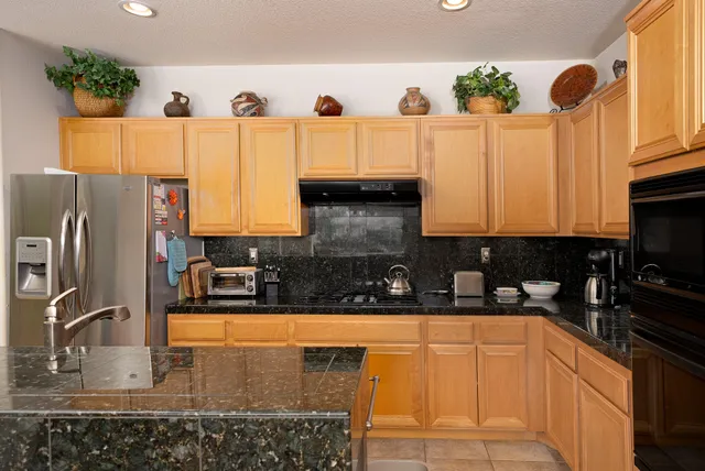 a kitchen with stainless steel appliances granite countertop a sink a stove and refrigerator
