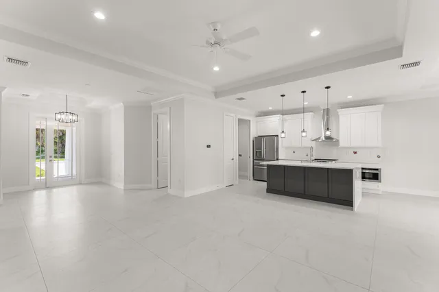 a large white kitchen with kitchen island a sink stainless steel appliances and cabinets