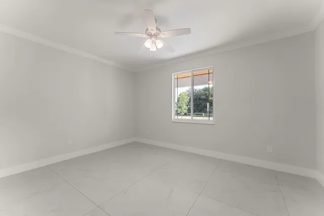 an empty room with a window and a ceiling fan