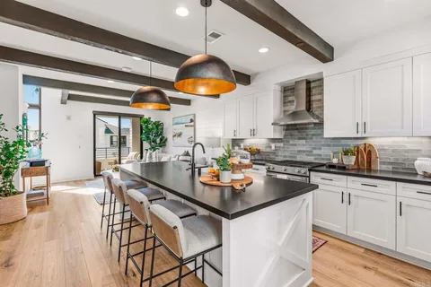 a kitchen with stainless steel appliances granite countertop a stove a sink dishwasher and white cabinets with wooden floor