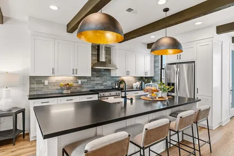 a kitchen with stainless steel appliances granite countertop a table chairs sink and white cabinets