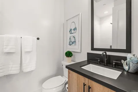 a bathroom with a granite countertop sink and a mirror with toilet