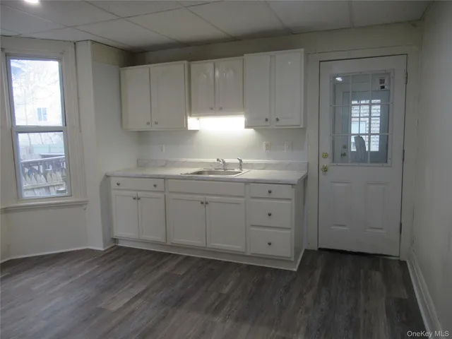 a view of cabinets a wooden floor and a window in an empty room