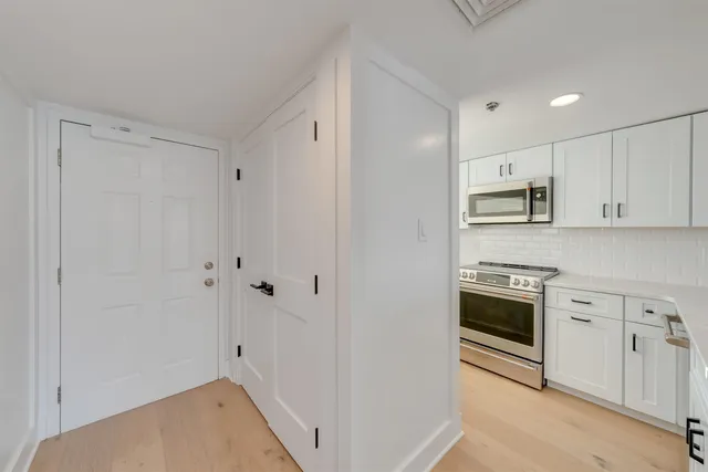 a kitchen with stainless steel appliances white cabinets and a stove top oven