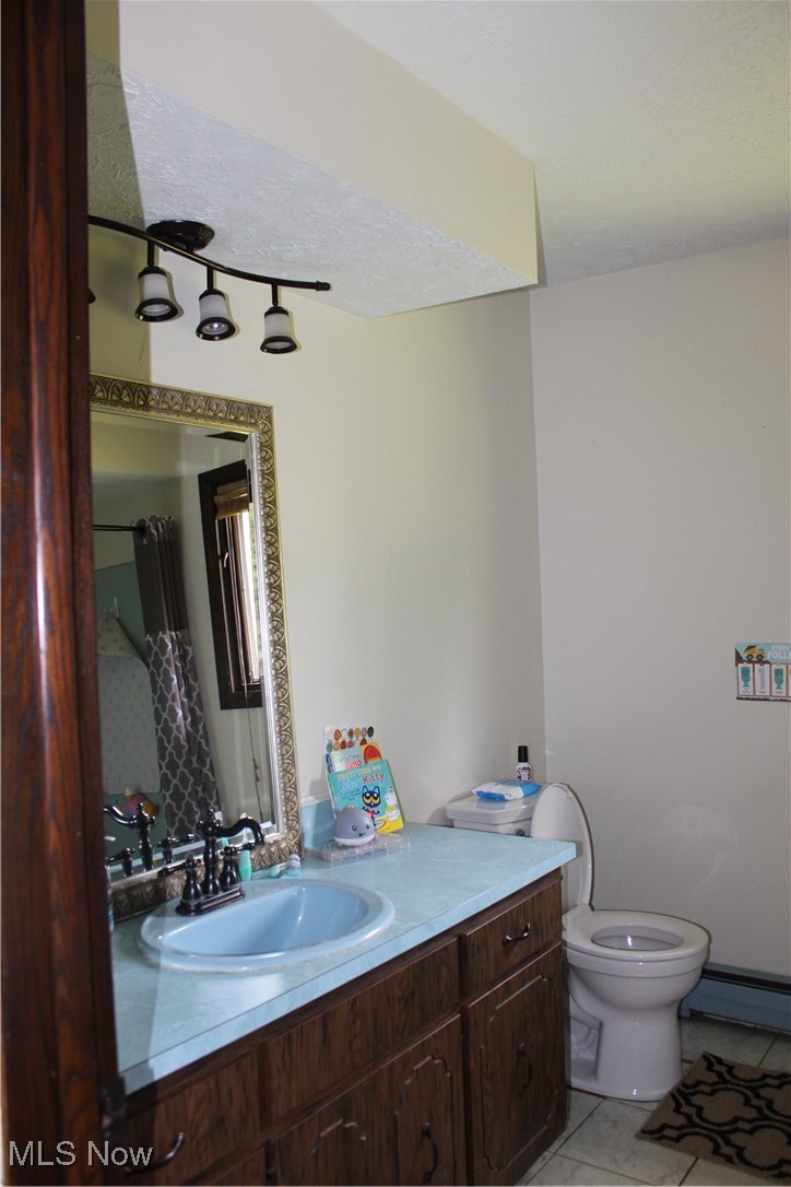 666 East Windsor Road Orwell, OH 44076 - Photo 9 of 33 Full bath featuring vanity, toilet, a baseboard radiator, and tile patterned flooring