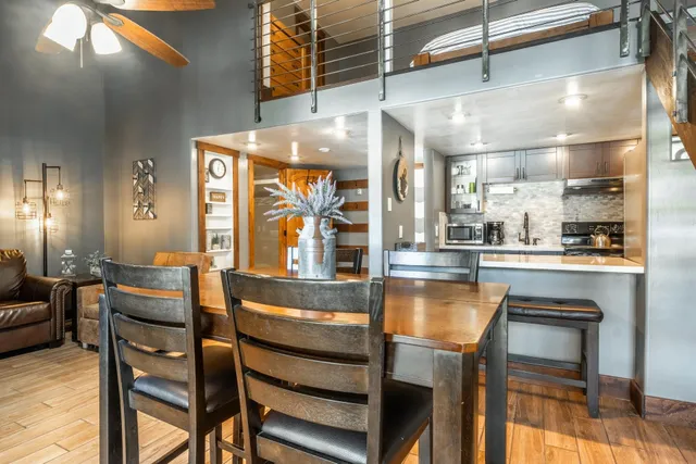 a dining hall with stainless steel appliances kitchen island granite countertop a table chairs and a living room view