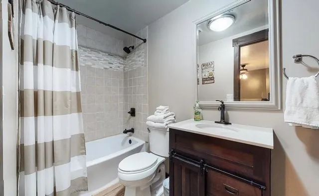a bathroom with a granite countertop sink toilet a mirror and shower