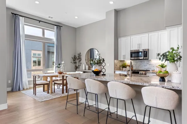 a kitchen with stainless steel appliances a dining table and chairs with wooden floor