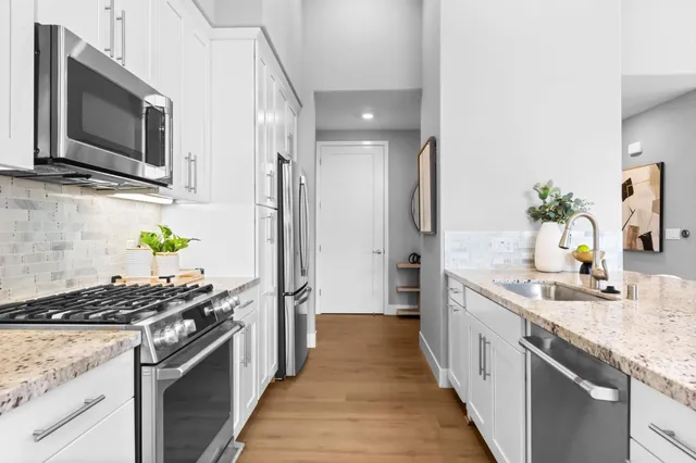 a kitchen with stainless steel appliances granite countertop white cabinets a stove top oven and a granite counter tops