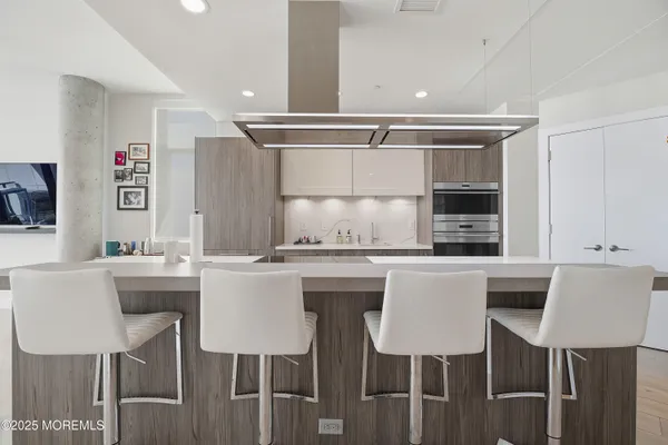 a kitchen with kitchen island a dining table chairs cabinets and sink