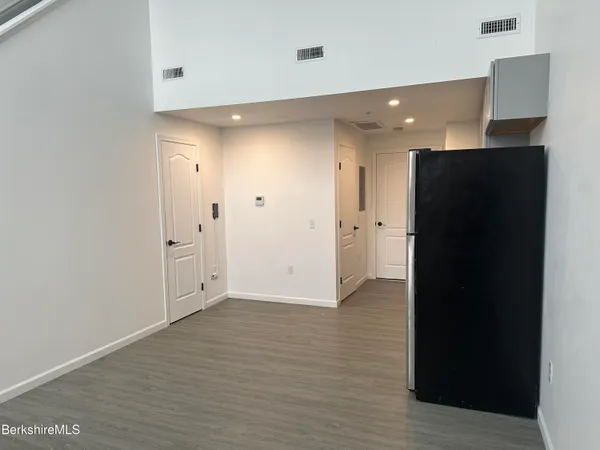 a view of an empty room with wooden floor and closet
