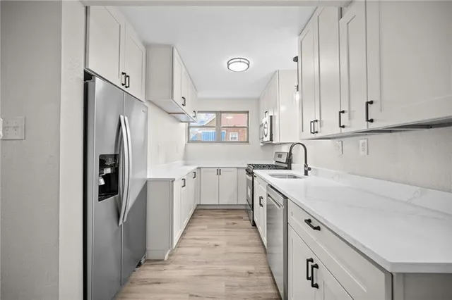 a kitchen with white cabinets and refrigerator