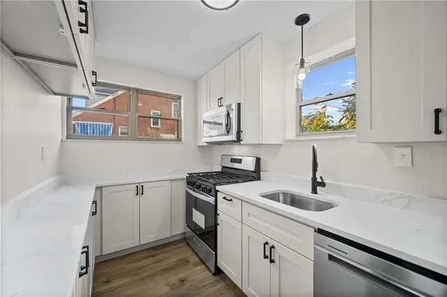 a kitchen with stainless steel appliances granite countertop a sink a stove and a wooden floors