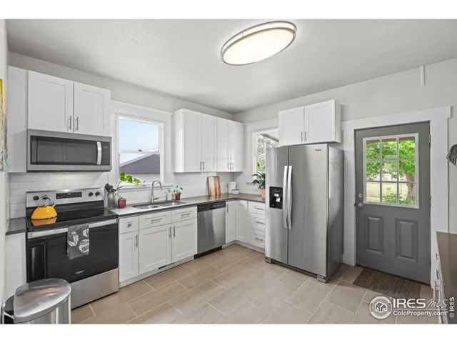 a kitchen with a refrigerator a microwave a sink and cabinets