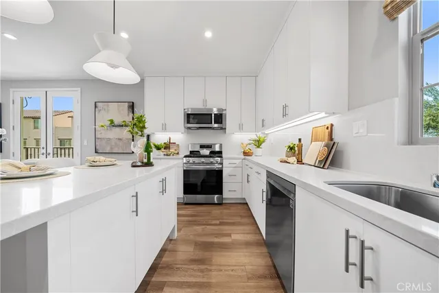 a kitchen with cabinets wooden floor and stainless steel appliances