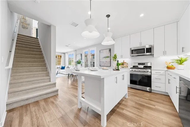a large white kitchen with stainless steel appliances granite countertop a stove and a sink