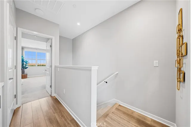 a view of a hallway with wooden floor and a bathroom