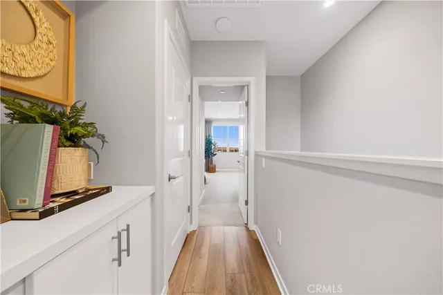 a view of a hallway with wooden floor and a bathroom