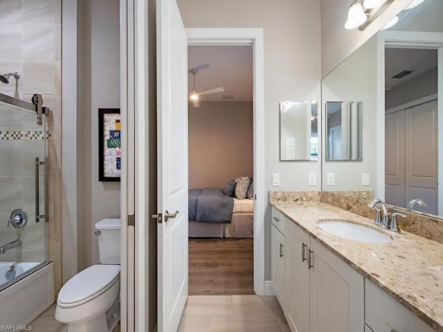 a bathroom with a granite countertop sink a toilet and shower