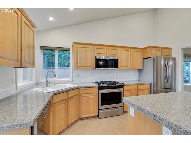 a kitchen with stainless steel appliances granite countertop a sink stove microwave and refrigerator