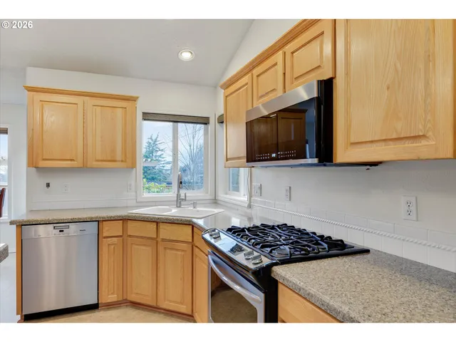 a kitchen with stainless steel appliances granite countertop a stove a sink and a microwave
