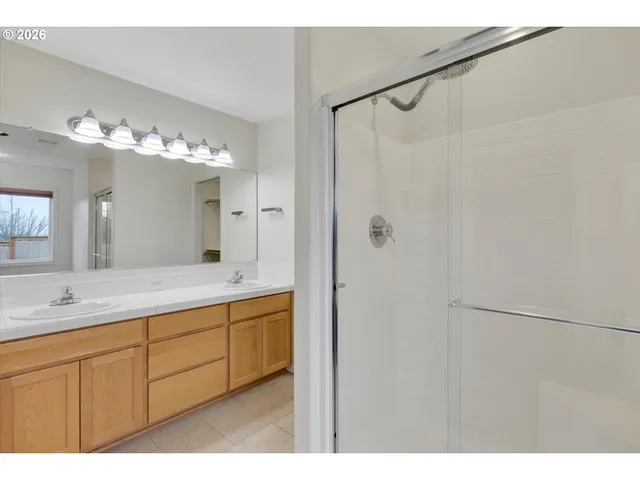 a bathroom with a double vanity sink mirror and shower