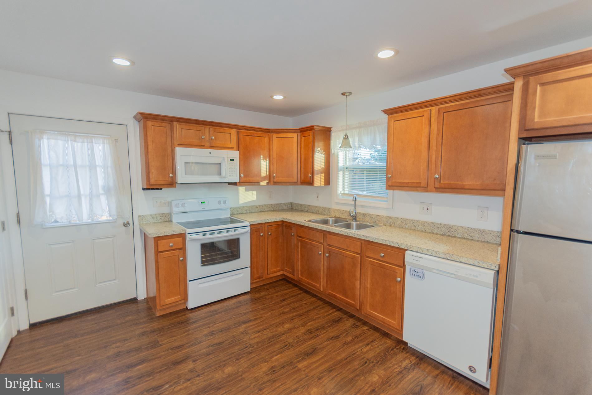 300 West 4th Avenue Ranson, WV 25438 - Photo 8 of 45 a kitchen with stainless steel appliances granite countertop wooden cabinets a sink a stove a refrigerator with wooden floors and a window