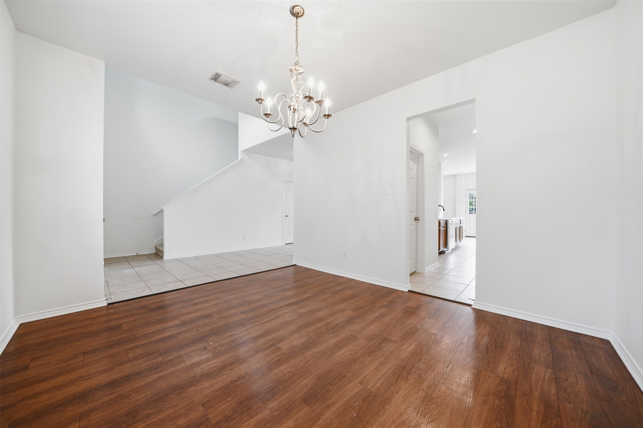 118 Invierno Street Kyle, TX 78640 - Photo 15 of 37 A graceful chandelier illuminates the rich wood flooring in this inviting dining area.