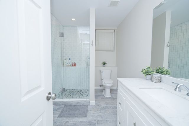 a bathroom with a granite countertop sink a toilet and shower