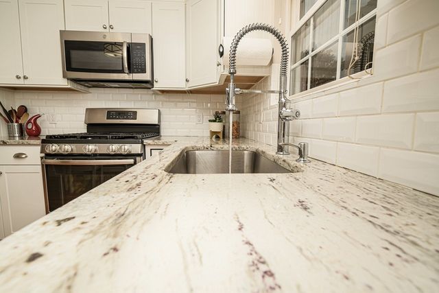 a kitchen with stainless steel appliances kitchen island granite countertop a stove top oven a sink a counter space and cabinets