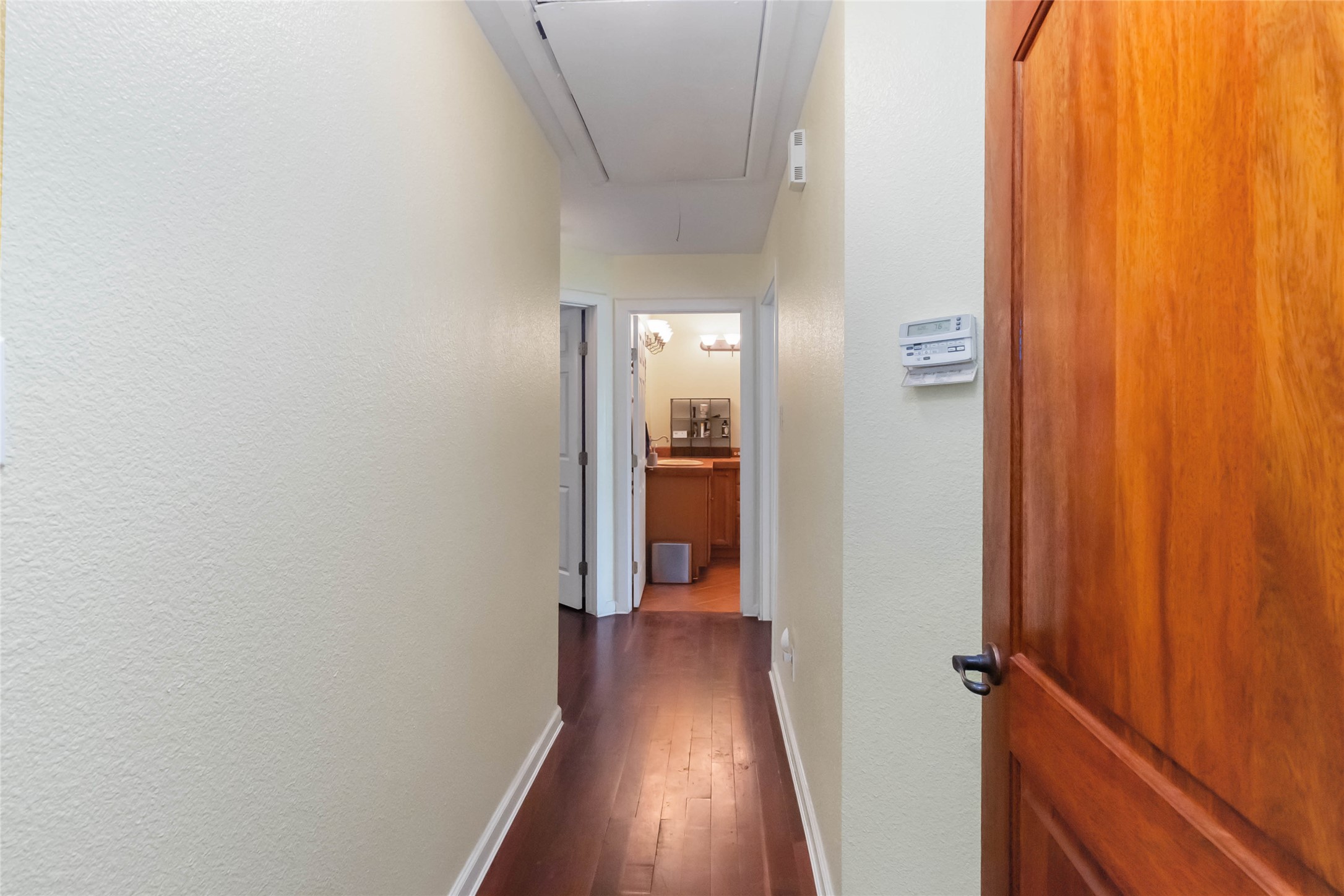 1208 Jeddo Road Rosanky, TX 78953 - Photo 16 of 40 Rich hardwood floors guide you down a sunlit hallway towards a well-appointed bathroom.