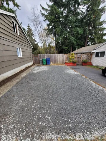 a view of an empty room with wooden floor and a kitchen