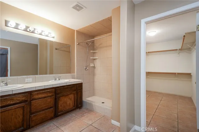 a spacious bathroom with a double vanity sink a mirror and a shower