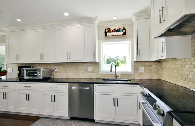 a kitchen with granite countertop white cabinets and white appliances