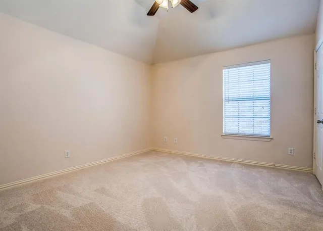 an empty room with a ceiling fan and window