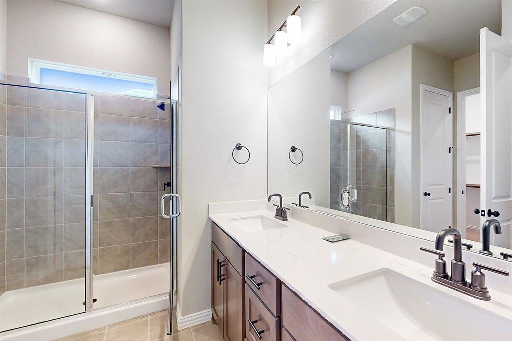 4907 Escape Rivera Drive Austin, TX 78747 - Photo 6 of 28 Dual vanities and a tiled shower create a functional, modern bath retreat.