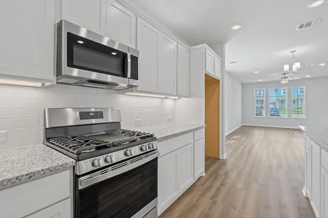 a kitchen with granite countertop a stove and a wooden floor