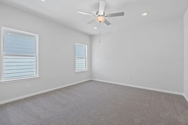 an empty room with windows and fan