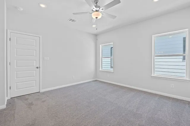 an empty room with windows and fan