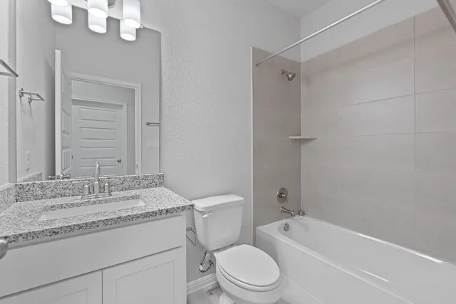 a bathroom with a granite countertop sink a toilet and shower