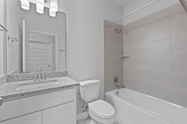a bathroom with a granite countertop sink a toilet and shower